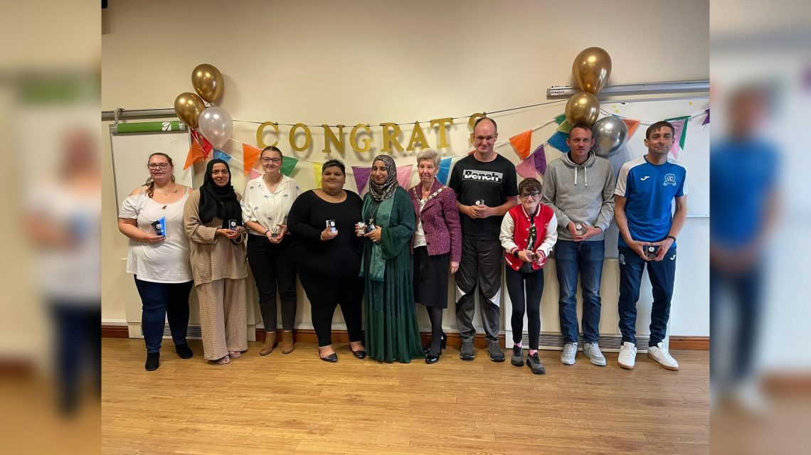 A group of people with awards at a ceremony.