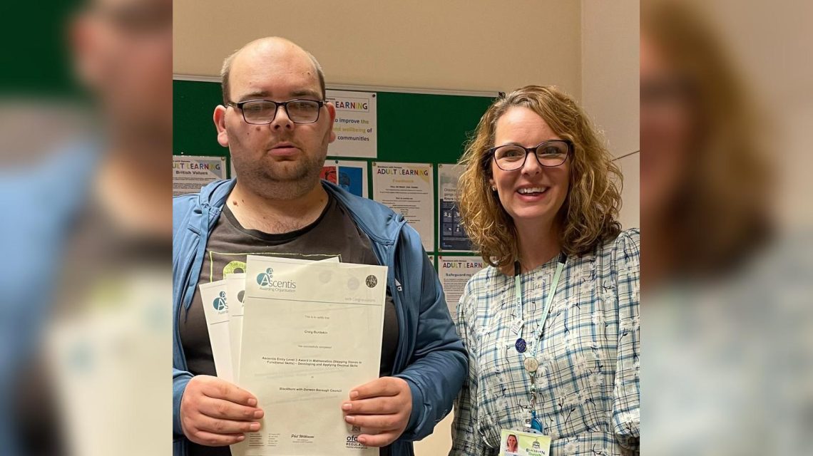 A man proudly holding certificates while standing next to a woman.